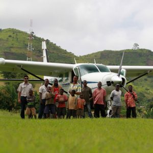 Group of children and men in front of plane mountains in background